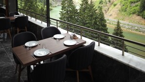 Un comedor con vista a un río y montañas.
