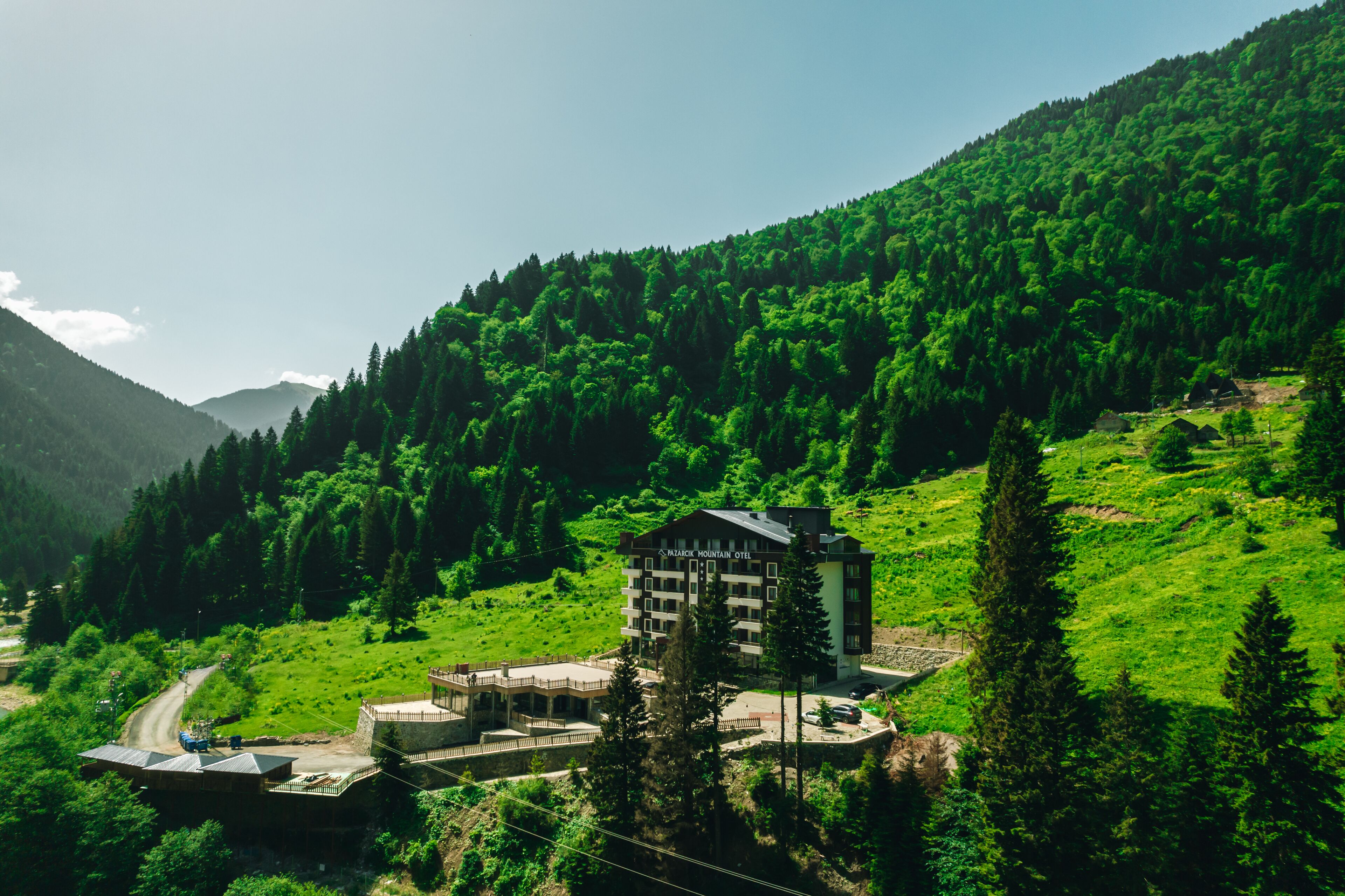 Un hotel de montaña con diseño moderno, rodeado de vegetación exuberante y colinas boscosas.