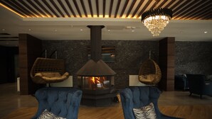 Una sala de estar moderna con chimenea, dos sillones azules y un asiento colgante.
