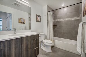 Ein modernes Badezimmer mit großem Spiegel, Waschbecken, Toilette und Duschbereich.