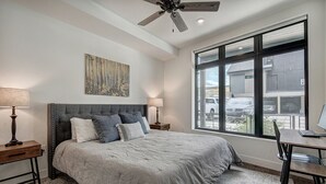 A bedroom with a large bed, a desk, and a window with a view of a parking area. - River West · Upscale Value, Centrally Located & Comfortable (Silverthorne)