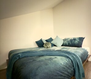 A bed with a blue and green patterned bedspread, a wooden headboard, and several pillows. - The Mont-Saint-Anne Landmark (Beaupré)