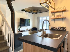 A modern kitchen with a central island, a built-in stove, and a 'WELCOME' sign. - The Mont-Saint-Anne Landmark (Beaupré)