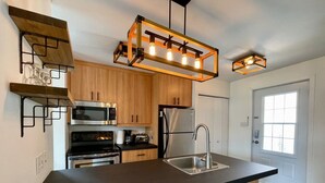 Una cocina moderna con una isla central, electrodomésticos integrados y una lámpara colgante.