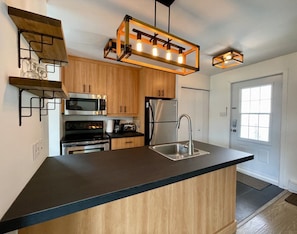 Een moderne keuken met een centraal eiland, inbouwapparatuur en een hanglamp.