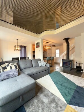 A modern living room with a sectional sofa, a fireplace, and a staircase leading to an upper level.