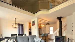 Un salon moderne avec un canapé d’angle gris, un tapis à motifs et une cheminée.