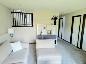 Relax in this serene living space with a comfortable sofa, floor lamp, and shelving unit.