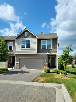 Stunning two-story home with a central garage door and beautifully manicured lawn.