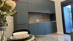 Une cuisine moderne avec des meubles gris, un pare-feu en bois et un coin repas avec une table dressée pour deux personnes.