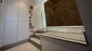 Un intérieur moderne avec un mur en pierre, un plafond en bois et une rambarde en verre.