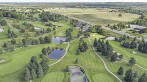 An aerial view of a golf course with multiple ponds, trees, and buildings. - Traverse city condo/golfing/beaches/wineries/hiking (Williamsburg)