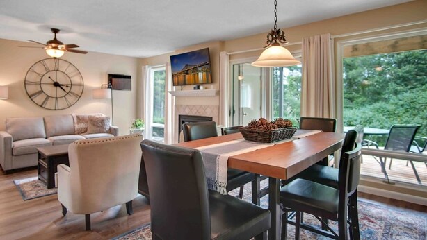 A dining area with a wooden table, black chairs, a chandelier, and a fireplace. - Traverse city condo/golfing/beaches/wineries/hiking (Williamsburg)