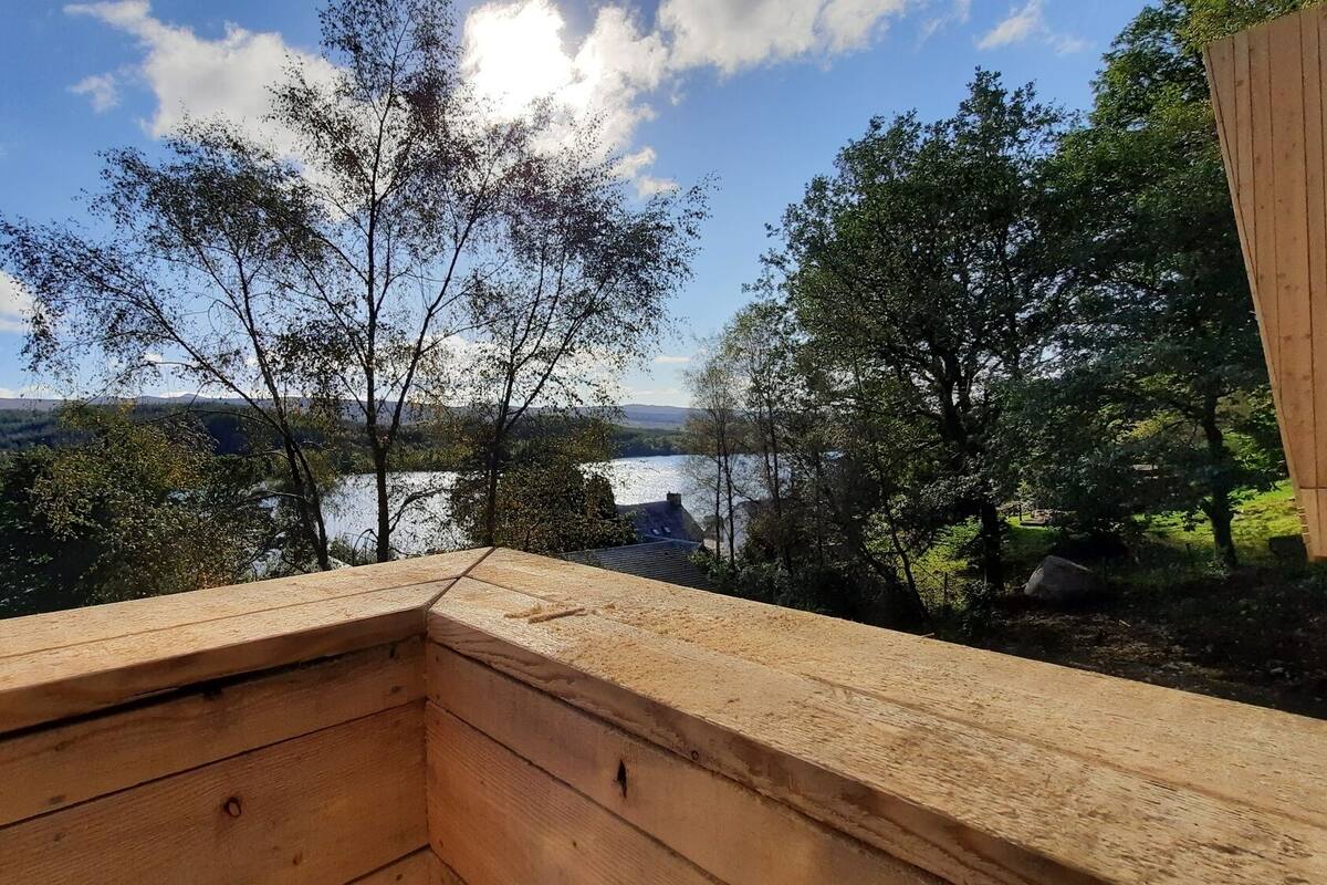 A wooden deck with a view of a lake and surrounding trees.