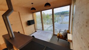 A modern room with a bed, a desk, and a large window with blinds. - Loch Awe Luxury Eco Cabins (Dalmally)