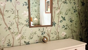 Un tocador con espejo, sobre un fondo de papel tapiz floral.