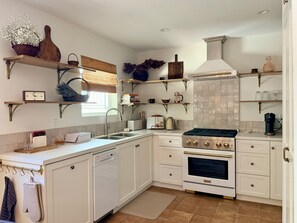 A kitchen with white cabinetry, a built-in oven, a sink, and various kitchen appliances.