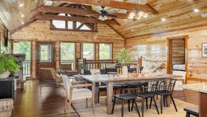 A spacious wooden cabin interior with a dining area, seating, and a fireplace. - Hot Tub + Pool Table + Pavilion | Smoky Mountain Views | Ridge View (Sevierville)