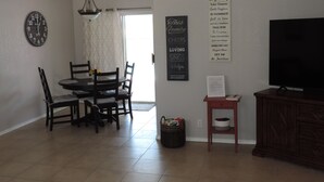 Un comedor con una mesa redonda y sillas, un reloj de pared, una lámpara de araña y una cita inspiradora en la pared.