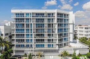 Un hotel de varios pisos con balcones, un área de piscina y vistas claras del barrio circundante.