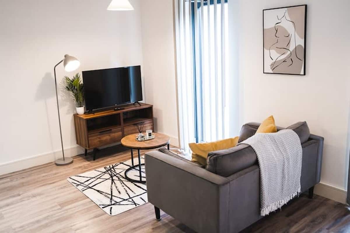 A modern living room with a flat-screen TV, a sofa, a coffee table, and a floor lamp.