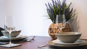 A dining table set with plates, bowls, and wine glasses, accompanied by a woven basket containing lavender. - Staycay - Modern 1-bed Apartment in Manchester City Centre (Salford)