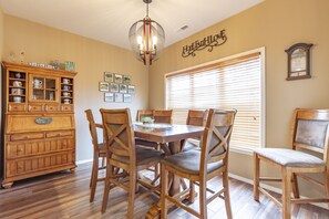 A dining area with a wooden table and chairs, a chandelier, and a cabinet with tea sets. - V1211-1, Golf-themed 2Br, 2Ba Villa on the 13th Fairway (Branson West)