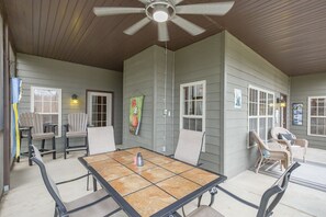 A covered patio with a table and chairs, a ceiling fan, and a door with a window. - V1211-1, Golf-themed 2Br, 2Ba Villa on the 13th Fairway (Branson West)