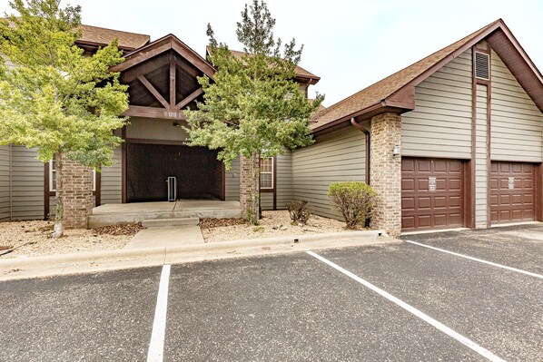 A building with a garage door, a brick entrance, and a parking lot. - V1211-1, Golf-themed 2Br, 2Ba Villa on the 13th Fairway (Branson West)