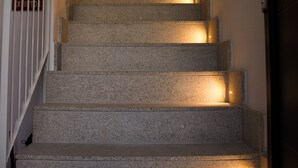 Un escalier avec une main courante sur le côté gauche et une porte en haut.
