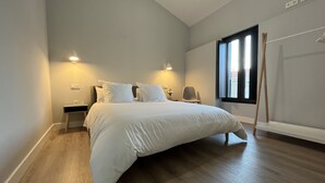 Une chambre avec un grand lit, deux tables de chevet, une chaise et une fenêtre donnant sur un beau paysage.