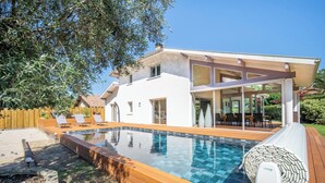 Una casa moderna con piscina, terraza y mobiliario exterior.