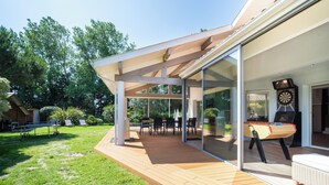 Un patio moderno al aire libre con terraza de madera, puertas correderas de vidrio y zona de comedor.