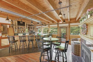A rustic interior with wooden beams, a bar area, and a dining space with chairs and a table. - Valley Escape (Thornton)