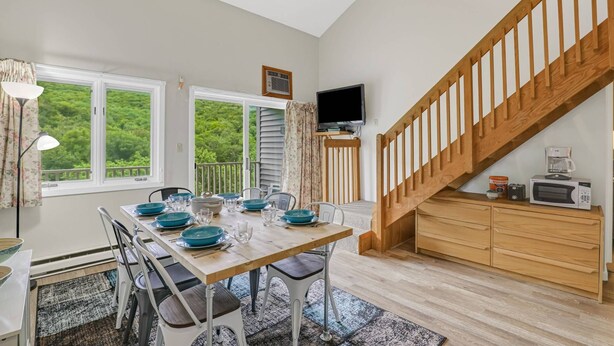 A dining area with a wooden table, chairs, and a TV mounted on the wall. - Lidos Lodge (Lincoln)