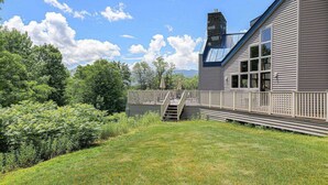 A house with a deck, a staircase leading to a covered area, and a view of the surrounding greenery. - Lidos Lodge (Lincoln)