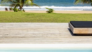 A wooden deck with a lounge chair and a small pool.