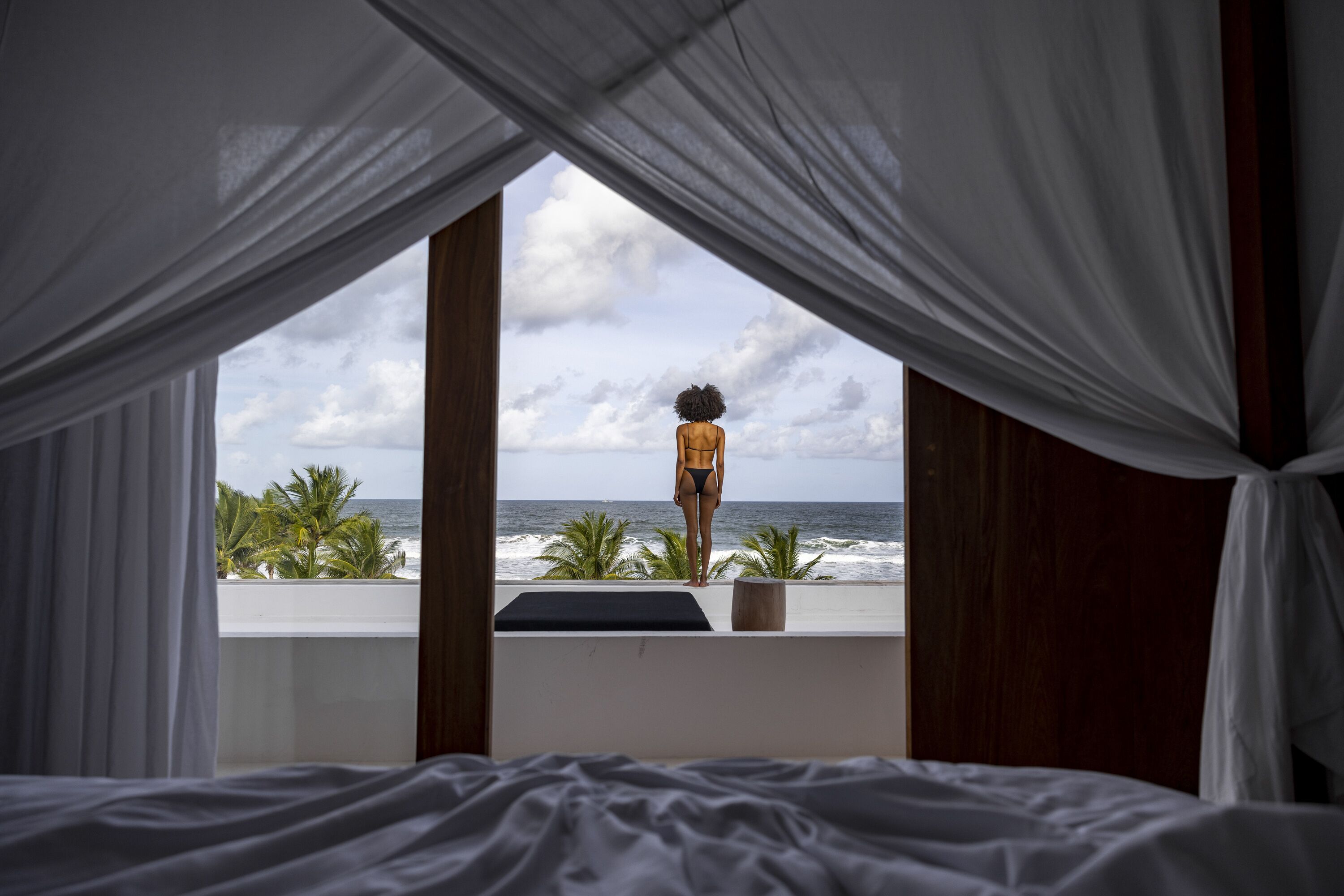 Quarto com vista para o oceano, uma cama e uma janela com cortinas.