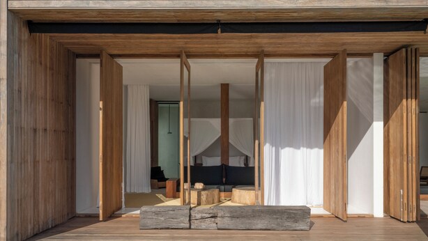 A modern room with a wooden floor, a bed with a canopy, and a view of a pool.