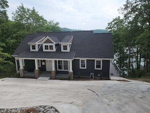 A two-story house with a dark roof, white trim, and a covered porch with stone pillars. - Large Lakefront home w/ Private Dock in Big Creek, beautiful views! (LaFollette)