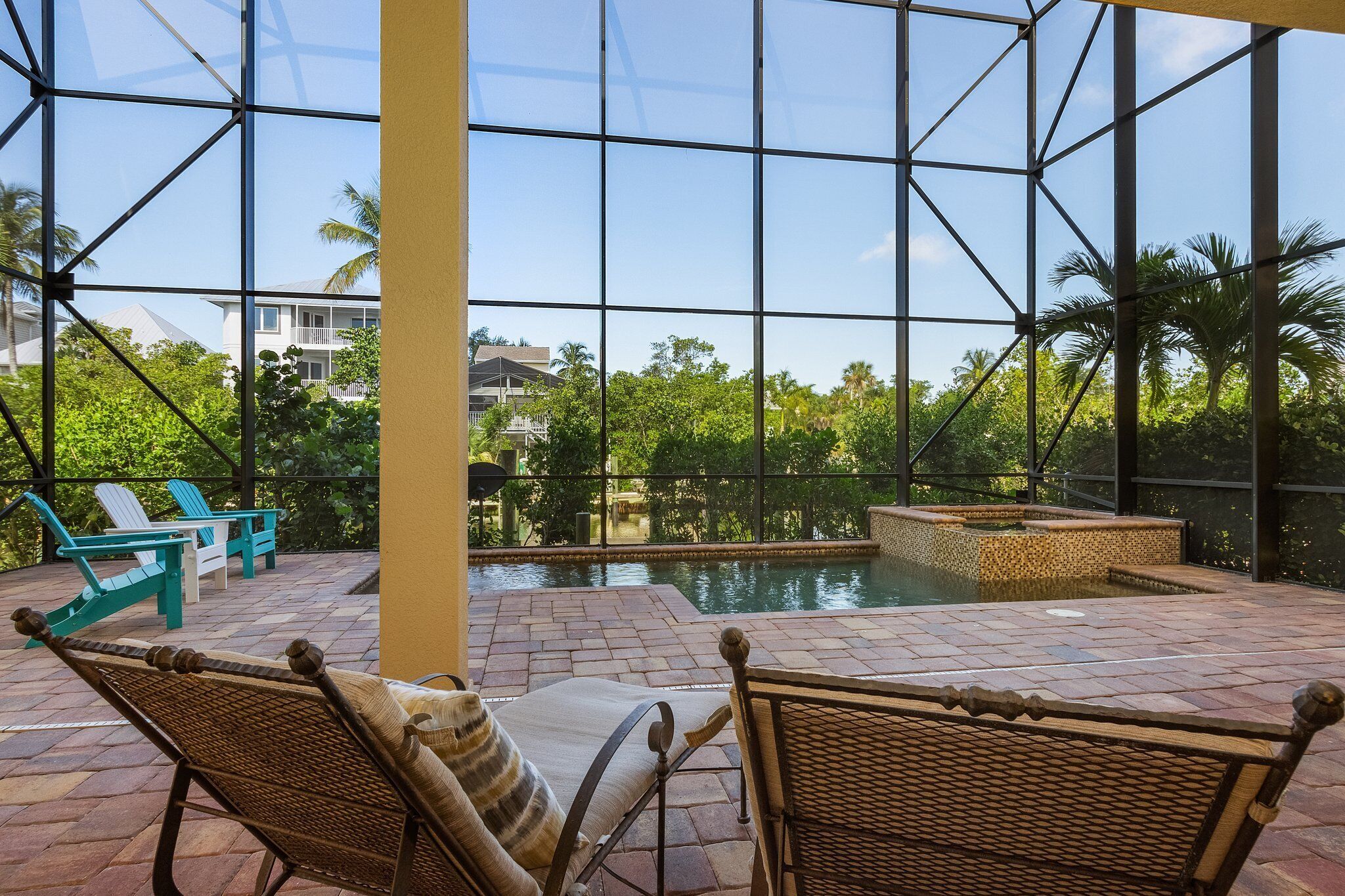 A pool area with wicker chairs and a view of a residential building through large glass windows.