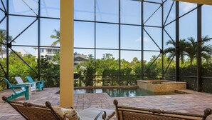 Área de piscina com cadeiras de vime e vista para um edifício residencial por grandes janelas de vidro.