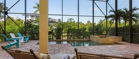 A pool area with wicker chairs and a view of a residential building through large glass windows.