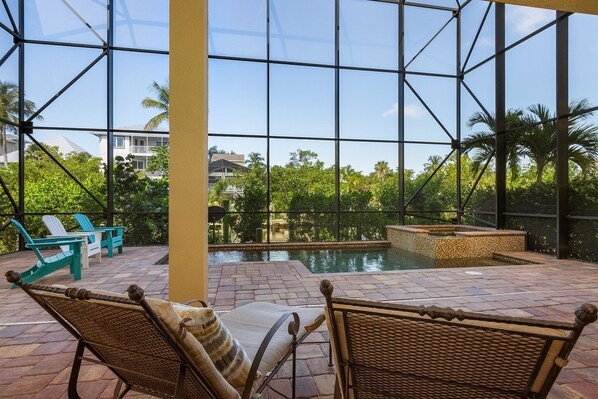A pool area with wicker chairs and a view of a residential building through large glass windows.