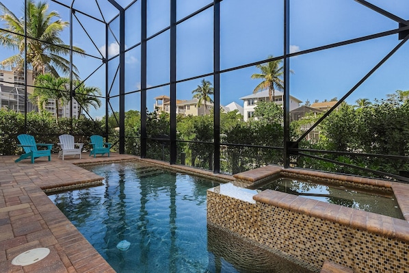 An indoor swimming pool with clear blue water, surrounded by a tiled deck and a glass enclosure.