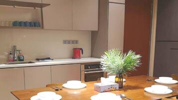 A compact kitchen with a dining table set for four, a coffee maker, and a potted plant.