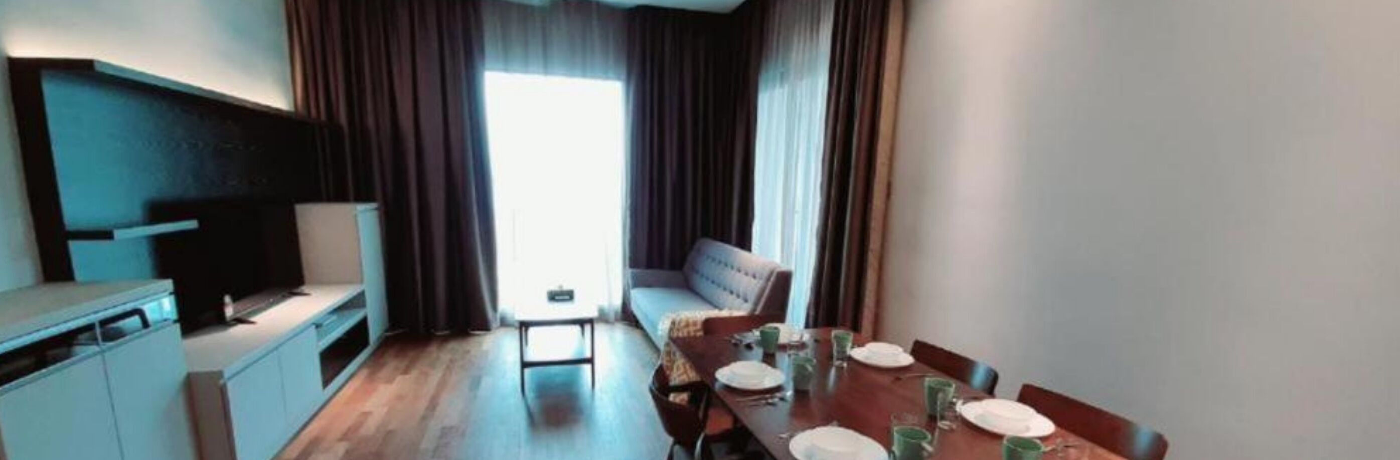 A compact living space with a kitchenette, a dining table set for two, and a sofa.