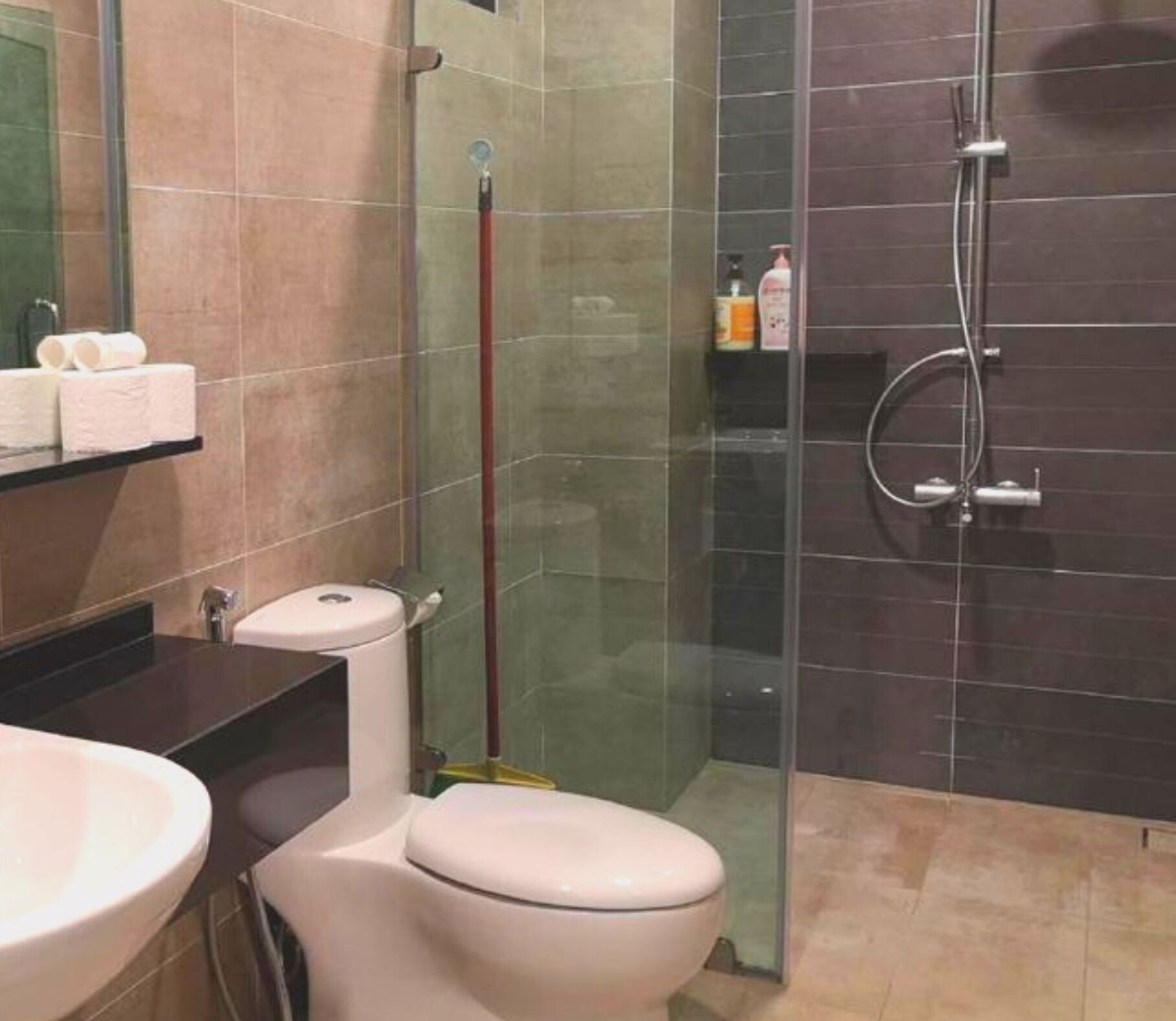 A bathroom with a toilet, sink, and shower area.