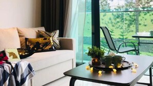 A modern living room with a sofa, a coffee table with a tray of lemons and a plant, and a balcony with a table and chairs.
