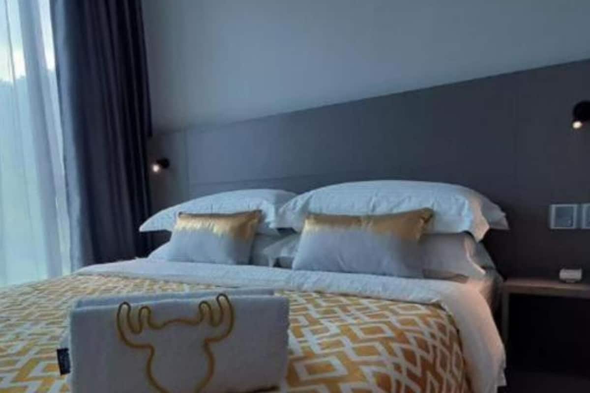 Une chambre d’hôtel avec un lit, une table de chevet et une fenêtre avec des rideaux.